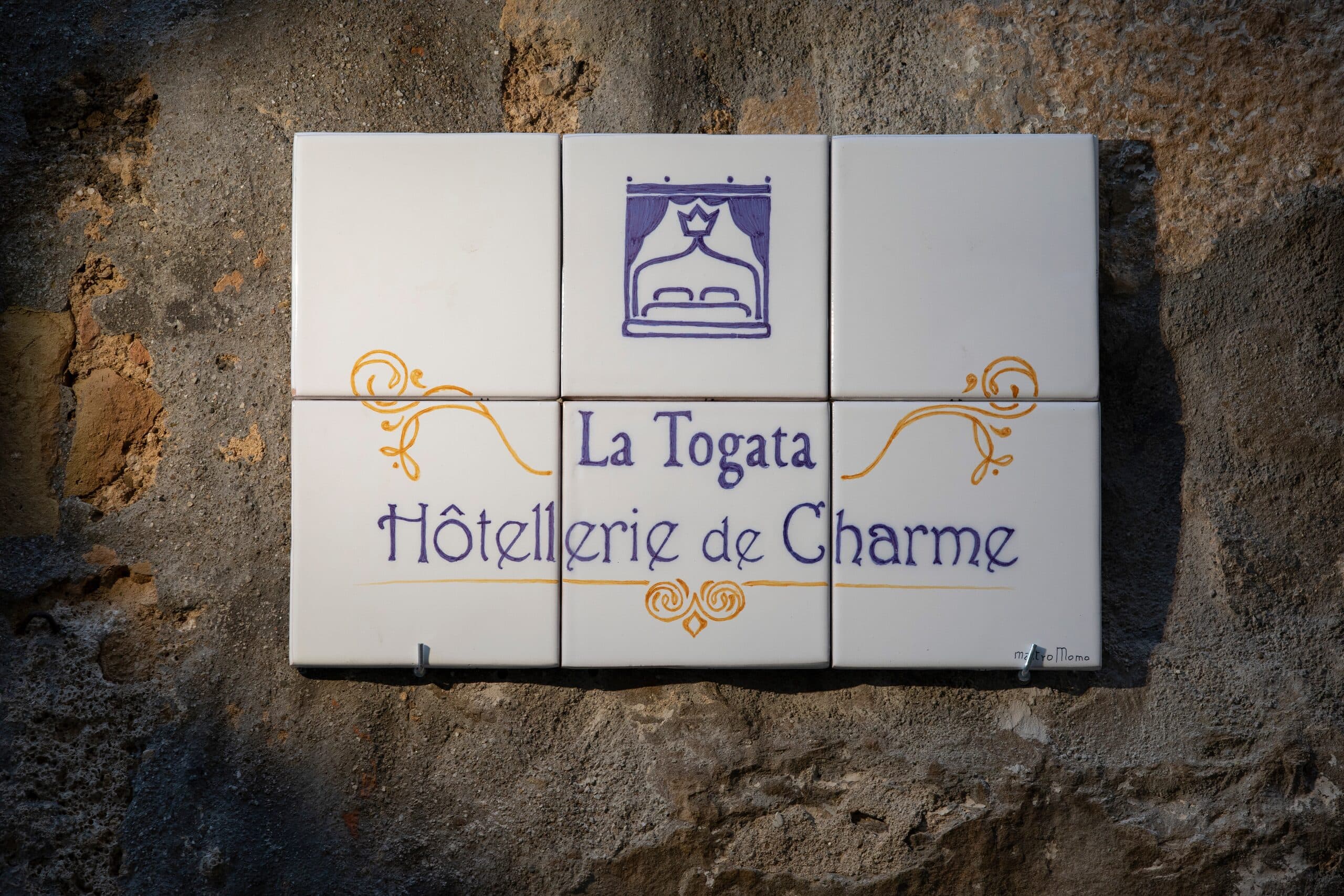 L'insegna in ceramica di La Togata Hôtellerie de Charme sulla parete in pietra