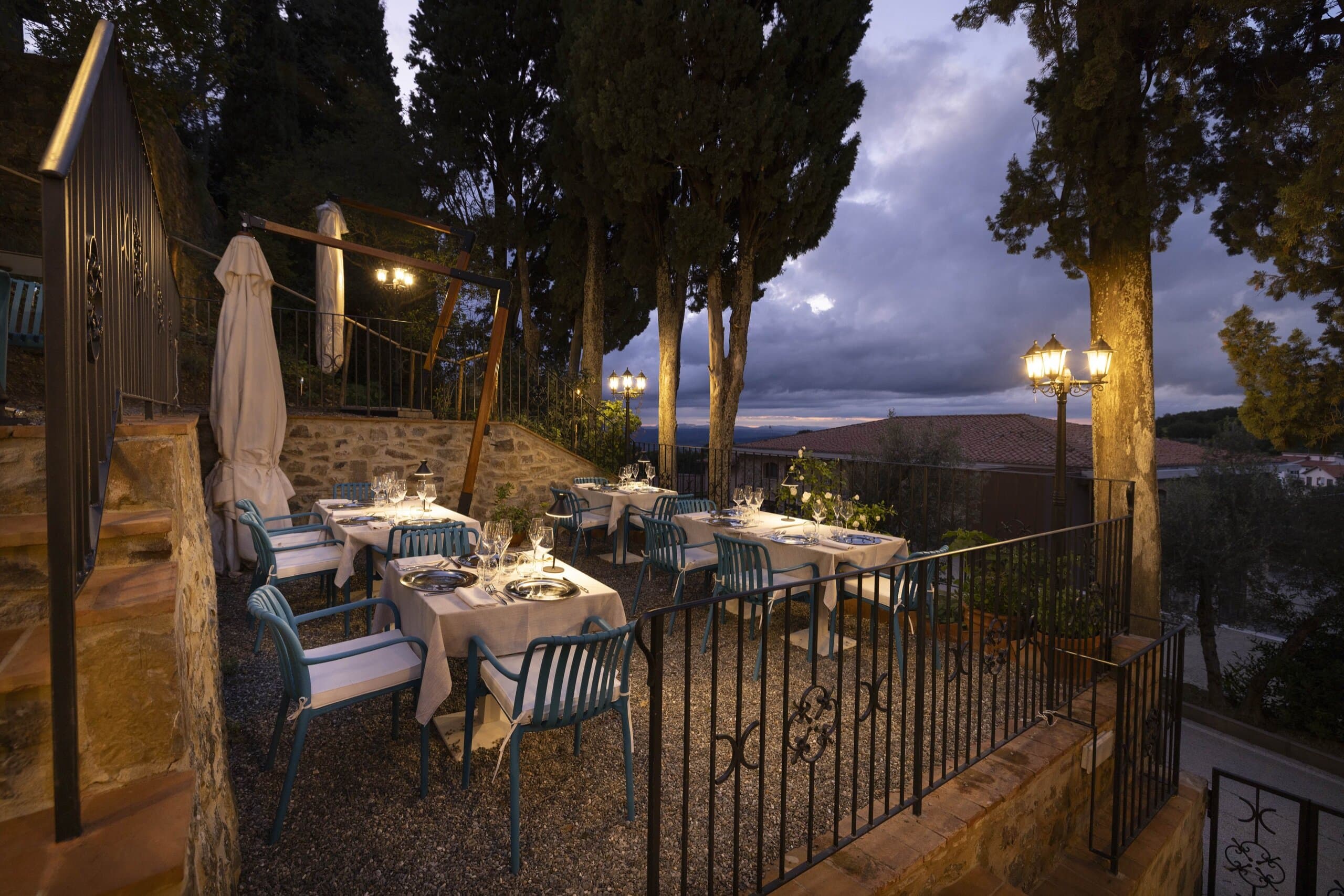La terrazza dell'Hosteria La Togata al crepuscolo, con i tavoli apparecchiati e la vista sulla Val d'Orcia