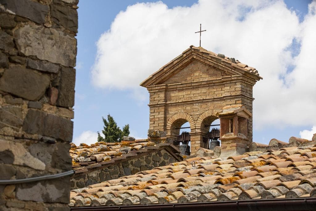 Il campanile della chiesa di Sant'Angelo in Colle sopra i tetti in cotto