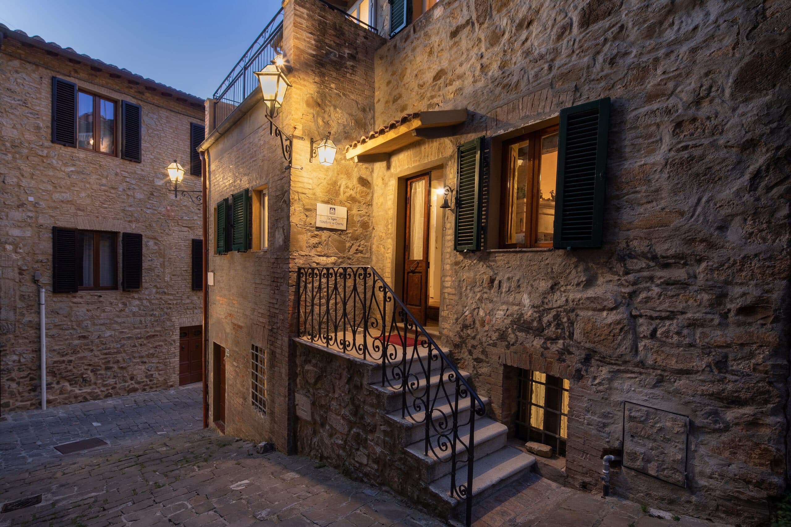 La facciata in pietra del Relais Il Pozzo illuminata al calar della sera