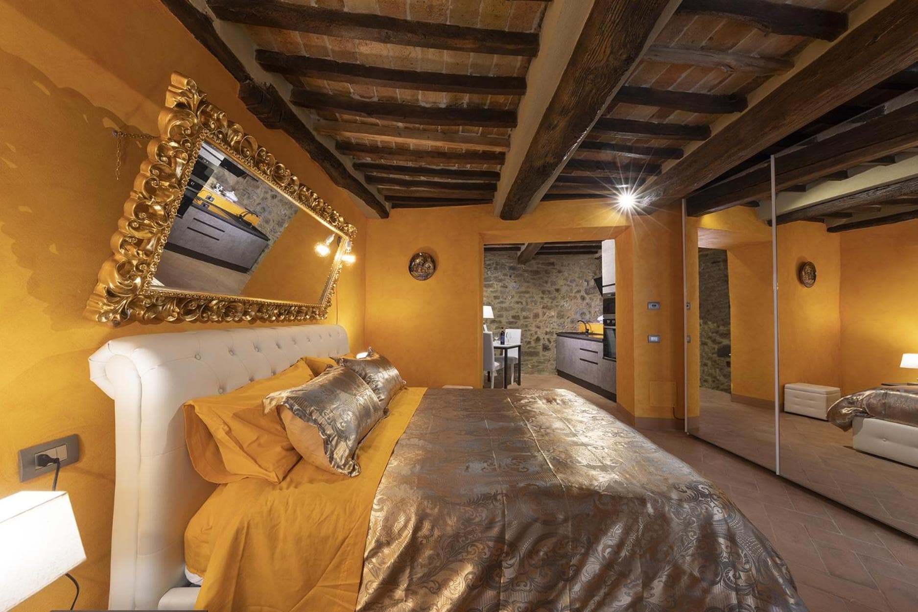The loft bedroom of the Oro, with exposed-rock wall and gilded mirrors