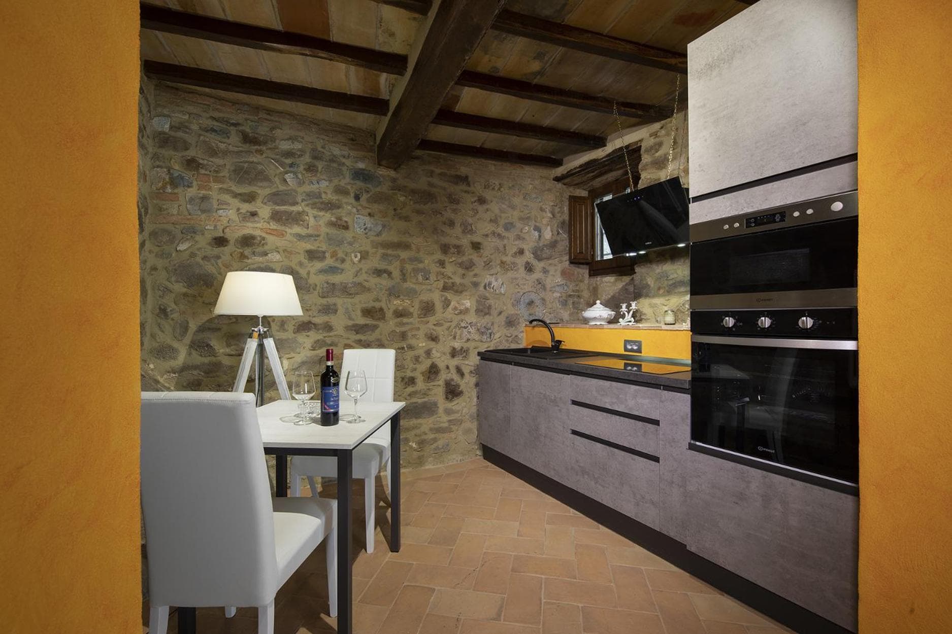 The private kitchen of the Suite dell'Oro, with exposed-rock wall and chestnut beams